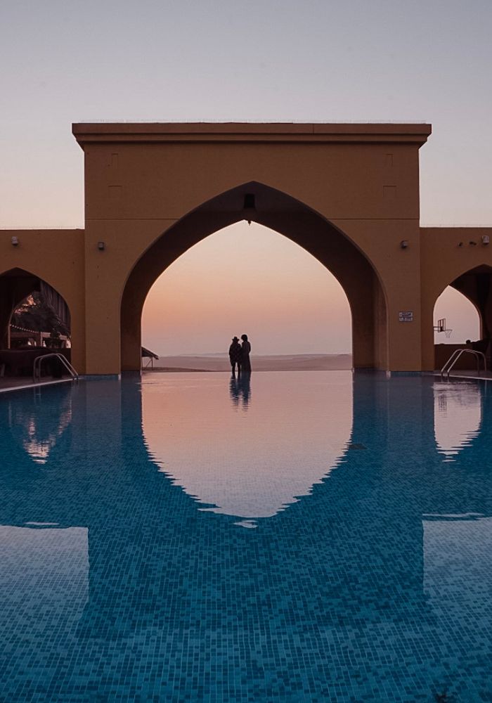 A blue swimming pool in front of the desert - a great place to relax after A Liwa Desert Safari!